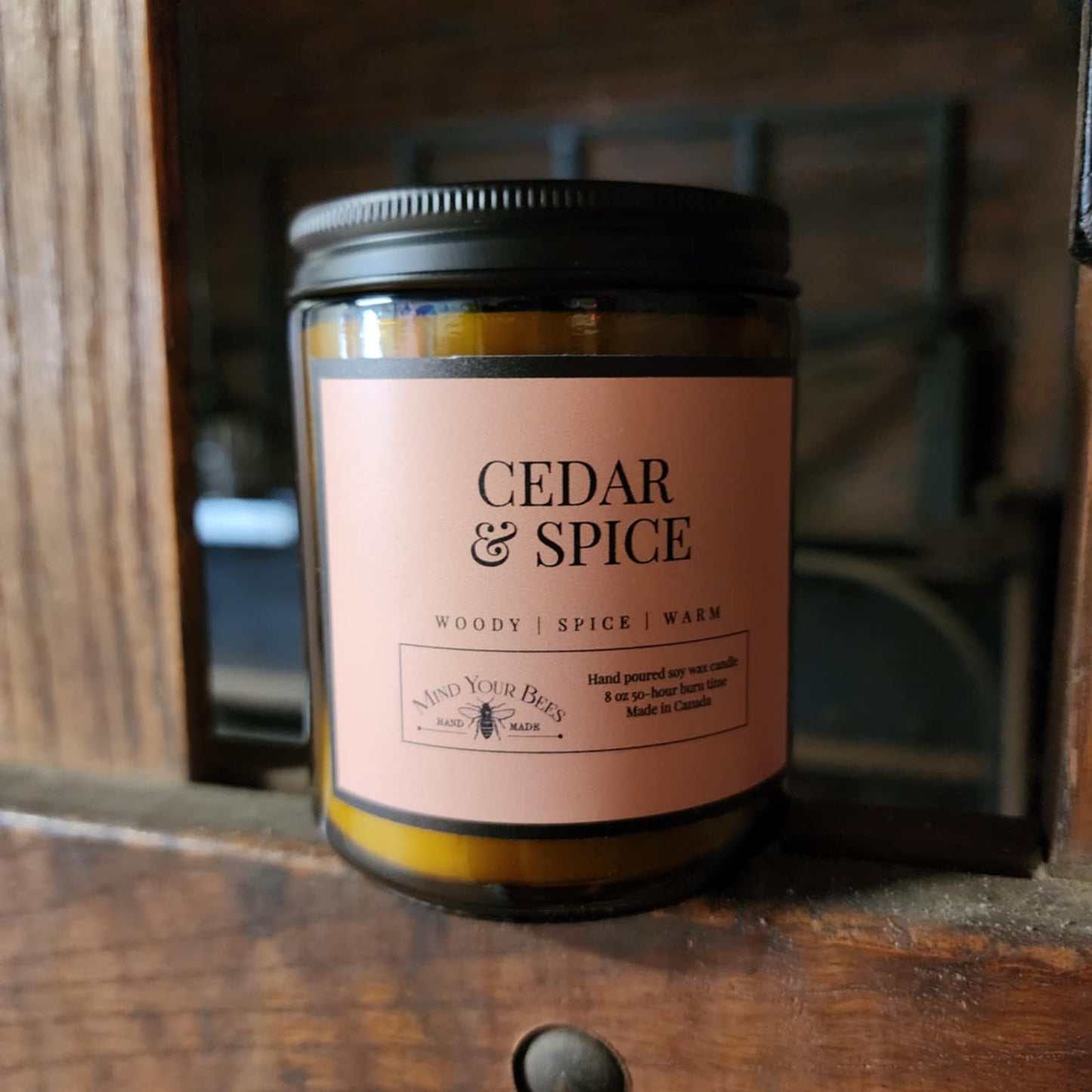 Candle labeled 'Cedar & Spice' on a wooden surface
