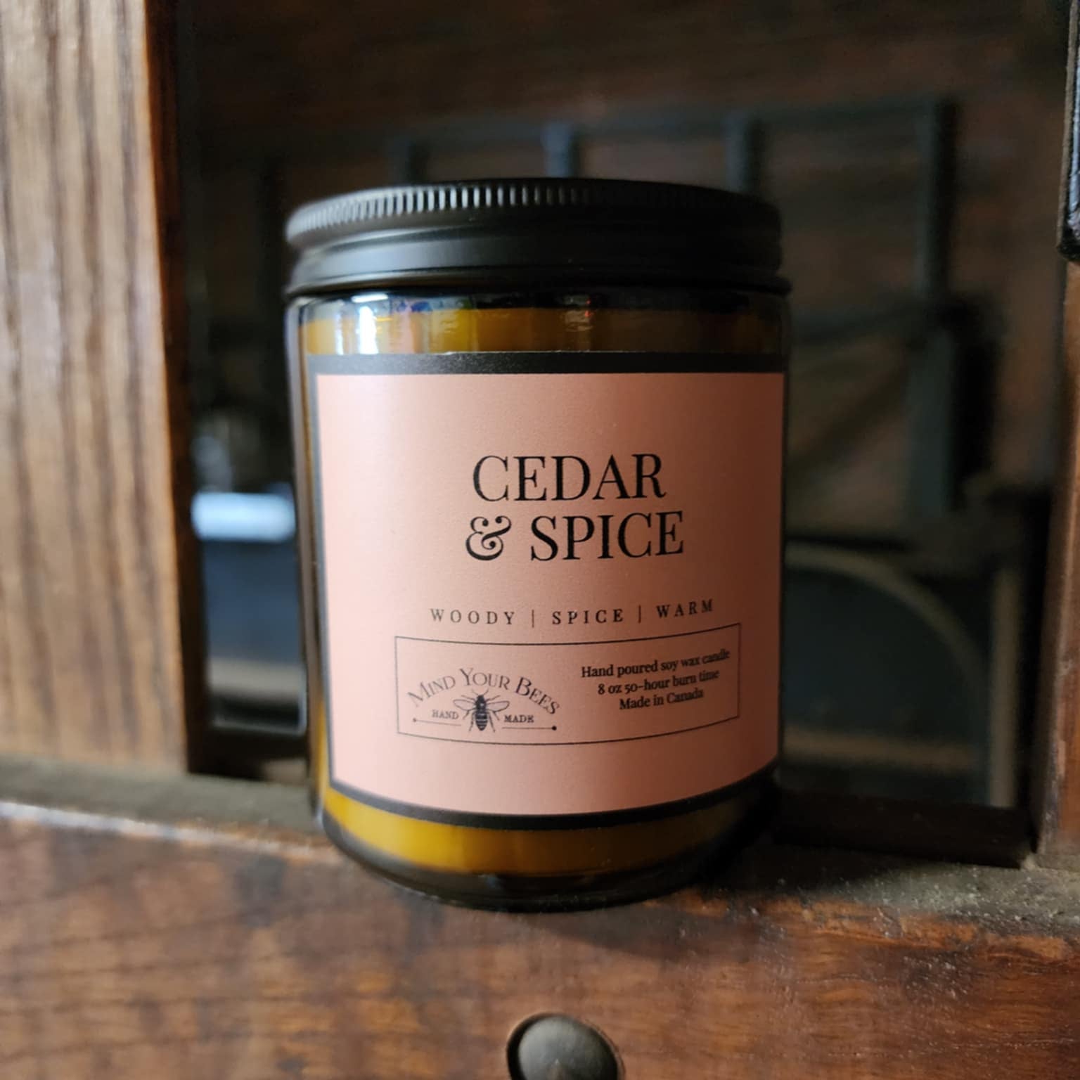 Candle labeled 'Cedar & Spice' on a wooden surface